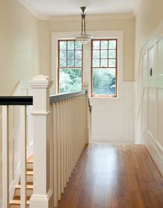 an empty hallway with wooden floors and white railings