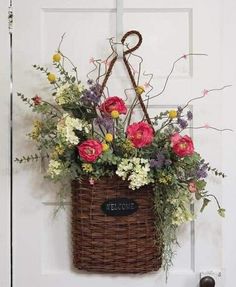 a basket with flowers hanging on the front door