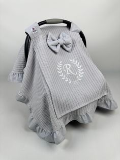 a gray blanket with a bow on it and a monogrammed ribbon around the neck