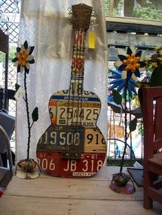 a guitar shaped sculpture sitting on top of a wooden table next to a white curtain