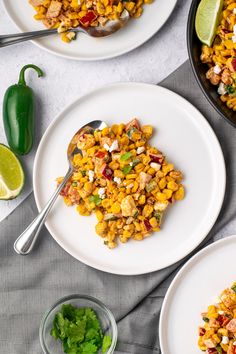 two plates with mexican corn salad on them next to lime wedges and cilantro