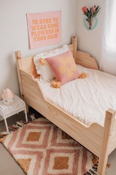 a bedroom with a bed, rugs and pictures on the wall above it that says be sure to wear some flowers in your hair