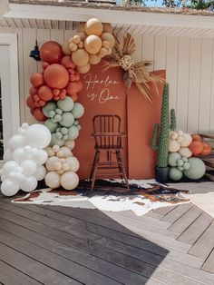 an orange and white balloon arch on a deck with chairs, cactus plants and other decorations