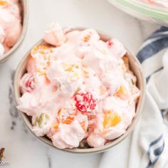 two bowls filled with fruit salad on top of a white marble counter next to cherries