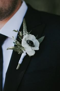 a man wearing a black suit and white boutonniere with flowers on it