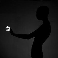 the silhouette of a man holding his hand out in front of him on a black background