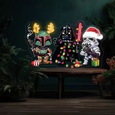 three star wars characters are sitting on a table with christmas lights in the shape of darth vader and stormtrooper