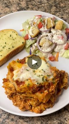 a white plate topped with lasagna covered in cheese and sauce next to a slice of bread