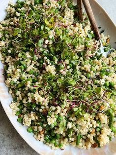 a white plate topped with a salad covered in veggies and sprouts