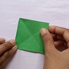 two hands are holding a piece of green paper