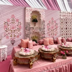 a pink and gold wedding reception setup with couches, plates and flowers on the table