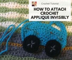 a crocheted blue car sitting on top of a blanket next to a pair of knitting needles