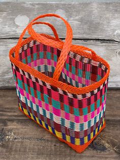 a multicolored woven bag sitting on top of a wooden floor