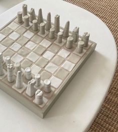 a chess board with white pieces on it and some cups in the backgroud