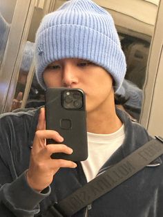 a man taking a selfie with his cell phone in front of him wearing a blue hat