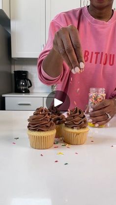 a woman is decorating cupcakes with chocolate frosting and sprinkles