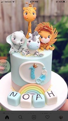 a hand holding a cake decorated with animals and letters