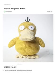 a crocheted yellow bird sitting on top of a wooden table next to a white wall