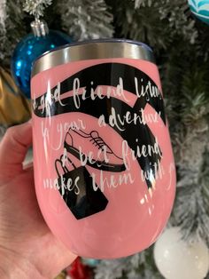 someone holding up a pink wine glass with black lettering