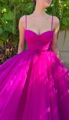 a woman in a bright pink dress is posing for the camera