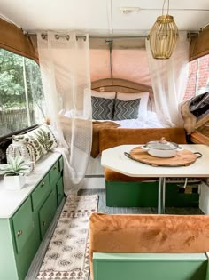 the inside of a camper with green cabinets and white curtains on the windowsill