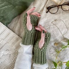 a pair of green knitted mittens sitting on top of a bed