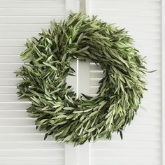 a wreath hanging on the side of a white door with shutters in front of it