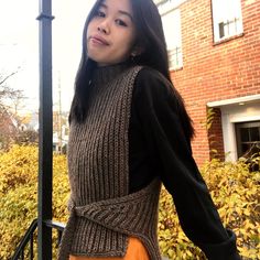 a woman standing next to a pole with her hand on her hip wearing an orange skirt