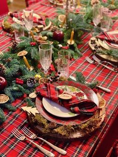 the table is set for christmas dinner with red and green plaid napkins on it