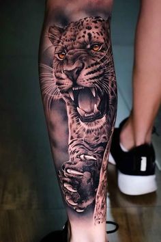 a man's leg with a tattoo on it that has a tiger and leopard