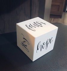 a white box with the words hope and believe written on it sitting on a table