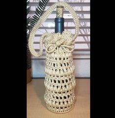 a crocheted bag with a bottle in the middle and a bow at the top