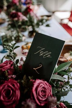 the table is set with red roses and place cards for guests to write their names