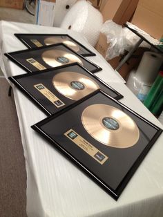 four gold discs are sitting on a white tablecloth in front of boxes and other items