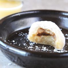 a powdered doughnut sitting on top of a black plate