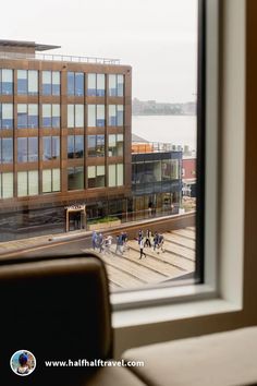 people are walking on the sidewalk outside an office building looking out at the water and buildings