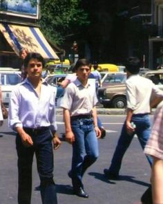 two men are walking down the street with other people