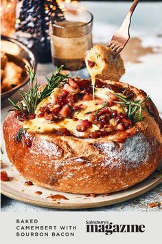 baked camemberi with bourbon bacon being served on a round bread dish topped with rosemary