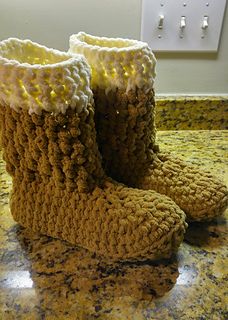 a pair of brown crocheted boots sitting on top of a counter next to a light switch