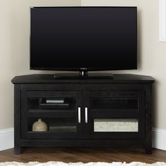 a flat screen tv sitting on top of a black entertainment center next to a white rug