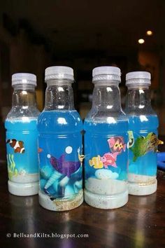 three plastic water bottles with fish and sea animals on them sitting on a wooden table