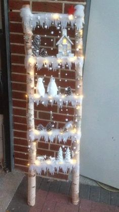 a ladder decorated with lights and snow on the side of a brick wall next to a refrigerator