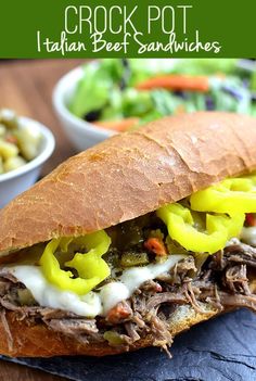 a close up of a sandwich with meat and vegetables in it on a plate next to a bowl of salad