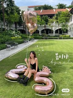 a woman sitting on the ground with balloons and letters in front of an apartment building