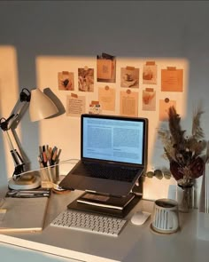 an open laptop computer sitting on top of a desk next to a lamp and other office supplies