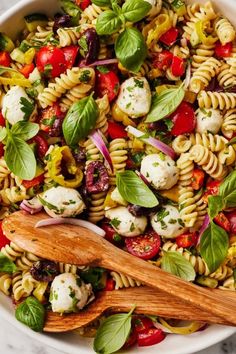 a pasta salad with tomatoes, mozzarella and basil