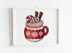 a cross stitch christmas mug with candy canes in it is hanging on the wall