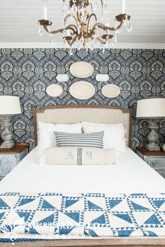 a bedroom with blue and white wallpaper, chandelier and bed in it