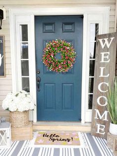 a blue front door with a welcome mat and flowers on the porch next to it