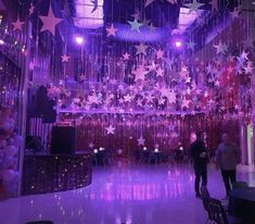 people are standing in the middle of a room with purple and pink decorations hanging from the ceiling